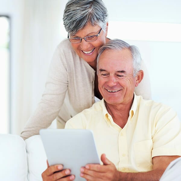 financial help for cancer patients & older couple reading ipad