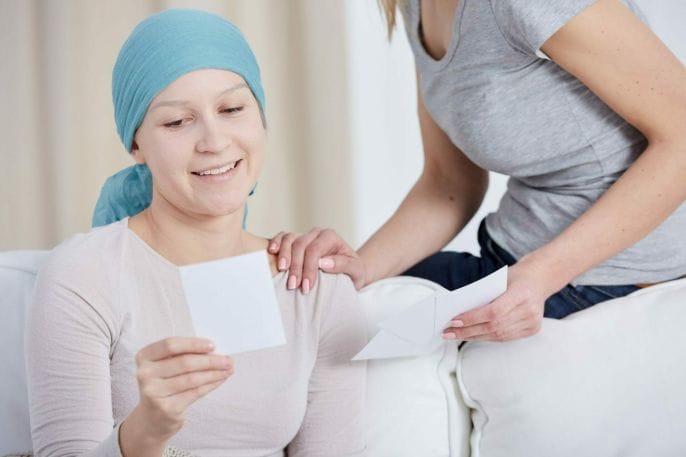 Smiling woman with cancer sitting on a sofa and looking at photo