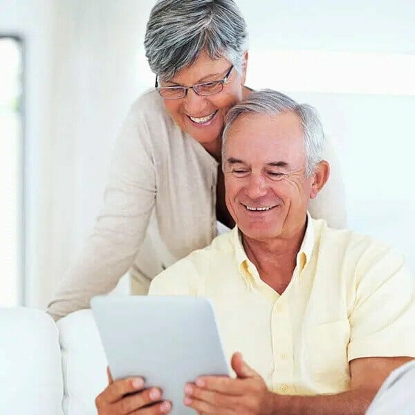 Cancer patient receiving help & older couple reading ipad