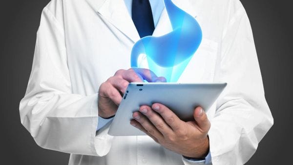 A medical professional in a white coat is holding a tablet from which a luminous, stylized graphic of a blue flame is emerging, symbolizing cutting-edge gastric cancer treatment. The image conveys the concept of modern and possibly expensive healthcare technology used in managing stomach cancer therapy expenses.