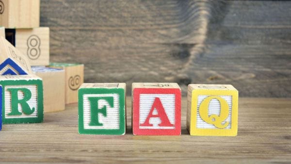 Colorful wooden blocks spelling out "FAQ" on a textured wooden surface, symbolizing frequently asked questions about renal cancer treatment costs. The blocks are in focus in the foreground with a blurred stack of other blocks in the background, suggesting a resource for information and answers.