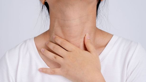 woman holding her neck, she has a sore throat 